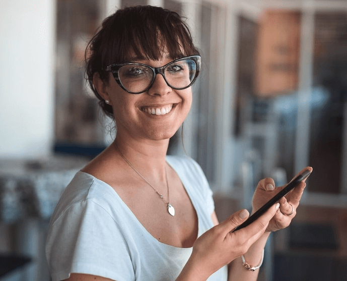 Eine Frau hält ein Smartphone in den Händen und lacht