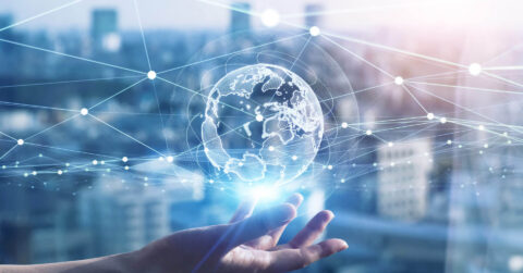 A hand holds a glowing digital globe with network lines and nodes, symbolizing global connectivity and the seamless communication enabled by the best SMS gateways Switzerland offers, against a blurred cityscape background.