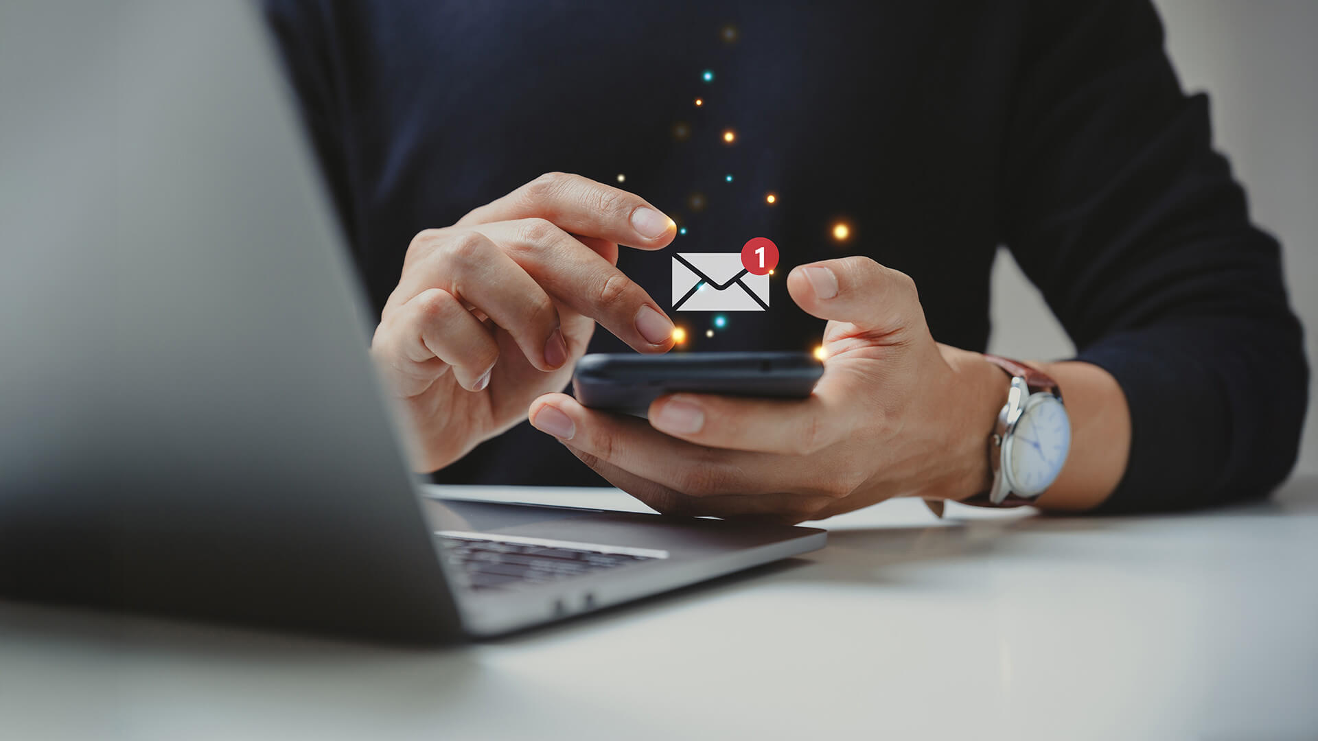 Person nutzt Smartphone neben Laptop und versendet digitale WhatsApp-Newsletter an Kunden für Business Messaging auf einer modernen Kommunikationsplattform
